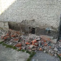 Odkopany fragment ściany z widocznymi uszkodzeniami, gruz i cegły. Rozpoczęcie prac, jak wzmocnić stare fundamenty z kamienia.