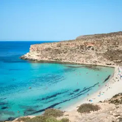 Sycylia pogoda w marcu: turkusowa woda, piaszczysta plaża z ludźmi i skaliste klify. Idealne warunki do wypoczynku.