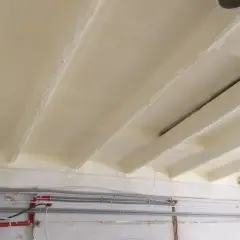 Ocieplony strop betonowy od spodu pianką PUR. Widoczne belki stropowe pokryte izolacją.