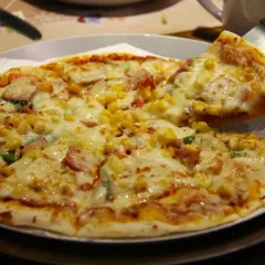 Pyszna hawajska pizza z ananasem, szynką i kukurydzą, właśnie podana.