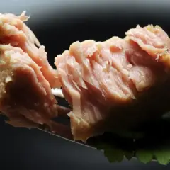 Kawałek tuńczyka z puszki na widelcu, z listkiem pietruszki. Czy pies może jeść tuńczyka z puszki? To pytanie nurtuje wielu właścicieli.