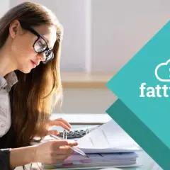 Donna con occhiali lavora su documenti e calcolatrice, assicurando la corretta fatturazione del centro medico privato.