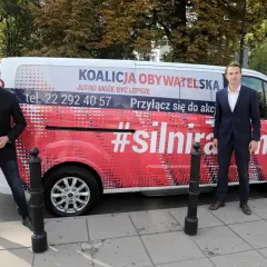 Dwóch mężczyzn stoi obok vana z napisem "Koalicja Obywatelska" i hasłem "#silnirazem".