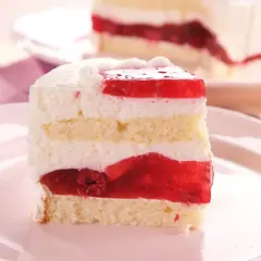 Ein saftiges Stück Frau Holle Kuchen mit Biskuit, Sahne und roter Fruchtschicht.