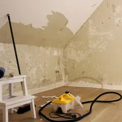 Tapete entsorgen: Dampfreiniger, Leiter und Werkzeuge liegen bereit. Die alte Tapete löst sich von den Wänden.