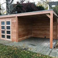 Neuer Holzschuppen mit Carport, das Dach ist mit Dachpappe verlegt. Herbstlaub liegt auf dem Boden.