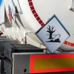 Zbliżenie na cysternę z oznaczeniami ADR. Widoczne symbole zagrożenia ekologicznego i łatwopalności.
