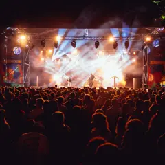 Un concerto illuminato da fari abbaglianti, con una folla entusiasta che partecipa a uno dei tanti **magnolia milano eventi**.