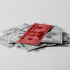 Stos dwudziestodolarowych banknotów, z jednym czerwonym na wierzchu, symbolizuje fundusz gwarantowanych świadczeń pracowniczych.
