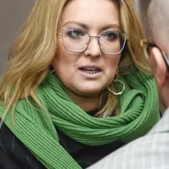 Kinga Burzyńska w zielonym szaliku i okularach rozmawia z mężczyzną.