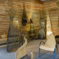 Atelier de vannerie. Des paniers, des luminaires et des sièges en osier, prêts à peindre de l'osier, décorent les murs en bois.