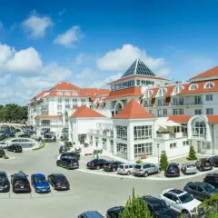 Elegancki hotel 5 gwiazdkowy nad morzem z dużym parkingiem i zielonym otoczeniem.