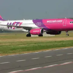 Samolot Wizz Air z różowym kadłubem i fioletowym ogonem na pasie startowym.