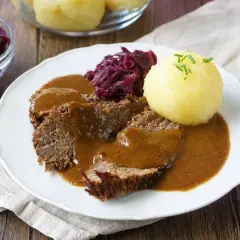 Sauerbraten rezept: Zarte Scheiben Braten in dunkler Sauce, serviert mit Rotkohl und Klößen. Ein Klassiker der deutschen Küche.