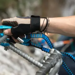 Ręka w rękawiczce z karabinkiem i lonżą, kluczowy element via ferrata sprzętu, zabezpiecza wspinaczkę.