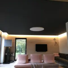 Nowoczesny salon z czarnym sufitem napinanym. Widać subtelne wady w postaci delikatnych zagnieceń na jego powierzchni.