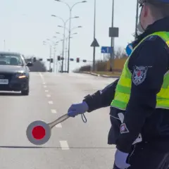 Policjant w kamizelce odblaskowej kieruje ruchem, zatrzymując audi. Nie ma tu fotoradaru, ale kontrola drogowa trwa.