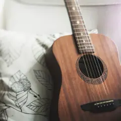 Akustyczna gitara obok poduszki z liśćmi. Idealna do grania harcerskie piosenki chwyty przy ognisku.