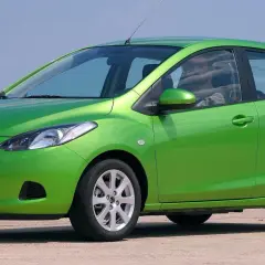 Zielona Mazda 2 DE z polskimi tablicami rejestracyjnymi WY 8177Y stoi na zewnątrz.