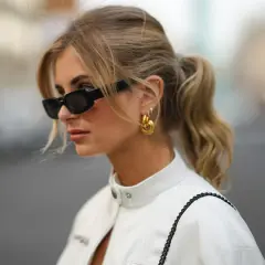 Mujer con gafas de sol y coleta, luciendo un estilo moderno con su flequillo cortina.