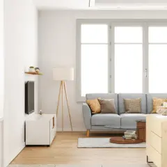 Salon lumineux avec canapé gris, table basse et grande fenêtre ouvrant à la française. Décoration moderne et épurée.