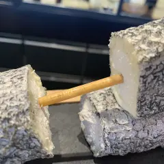 Deux morceaux de fromage de chèvre, un "tête de maure", sont reliés par un bâtonnet en bois.