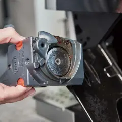 Dłoń wyjmuje brudny moduł młynka do kawy z ekspresu DeLonghi. Czas na czyszczenie, by cieszyć się aromatem!