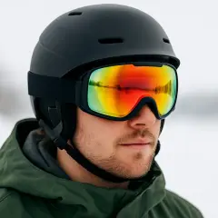 Mężczyzna w czarnym kasku na snowboard i goglach z kolorowym lustrem. Idealny zestaw na stok, by czuć się bezpiecznie i stylowo.