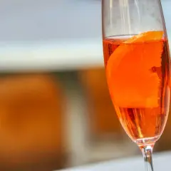 Orzeźwiający lillet drink z plasterkiem pomarańczy w kieliszku, gotowy na letnie popołudnie.