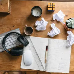 Bureau de travail avec clavier, casque, souris, carnet, brouillons et plante. Idéal pour rédiger une lettre de motivation fonction publique territoriale.