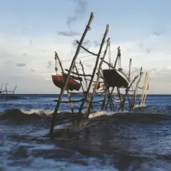 Barcas colgadas en estructuras de madera sobre el mar agitado, un paisaje evocador de lebeche en Rodalquilar.