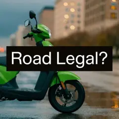 Zielony motorower z kaskiem na siedzeniu, stojący na mokrej ulicy. Czy to motorower co to, legalny na drogach?