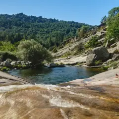Una mujer descansa junto a unas pozas en Madrid, rodeada de naturaleza y rocas.