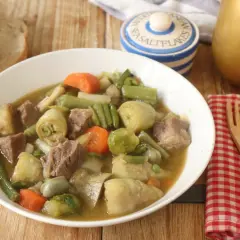 Un reconfortante plato de menestra de ternera con trozos de carne tierna y verduras como alcachofas, judías verdes y zanahorias.