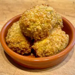Goldbraune spanische Kroketten, knusprig paniert, in einer Tonschale. Ein leckeres spanische kroketten rezept zum Genießen.
