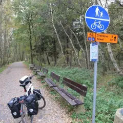 Ścieżka rowerowa Velo Baltica w jesiennym lesie. Rower z sakwami czeka obok ławek.