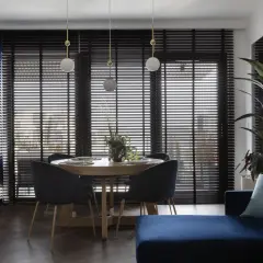 Elegancka jadalnia z okrągłym stołem i krzesłami w kolorze navy. Obok kuchnia z szafkami w tym samym odcieniu.
