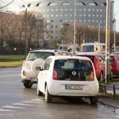Biały Volkswagen up! i inne samochody stojące na jezdni, częściowo zasłaniające przejście dla pieszych.