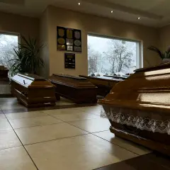 Wnętrze zakładu pogrzebowego z kilkoma drewnianymi trumnami.