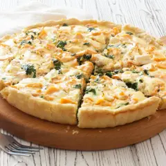 Pyszna tarta z łososiem, szpinakiem i serem feta, pokrojona na kawałki, czeka na talerzu.