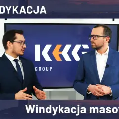 Dwóch mężczyzn w garniturach stoi przed ekranem z logo KK GROUP.