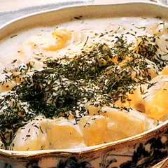 En krämig stuvad potatis med dill, serverad i ett vackert fat. En klassisk svensk rätt som värmer själen.