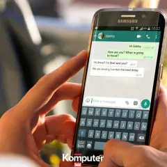 Dłonie trzymające smartfon z otwartym WhatsAppem. Widoczna klawiatura i okno czatu, jak założyć WhatsAppa.