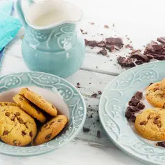 Schokoladenkekse, ein Krug Milch und zerbrochene Schokolade – perfekt für ein leckeres Cookies Rezept.