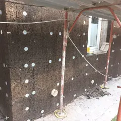 Pannelli di sughero espanso per cappotto termico, fissati con dischi bianchi. Lavori in corso su un edificio.