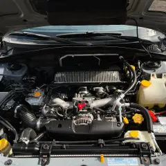 Silnik Subaru z widocznym zbiorniczkiem płynu chłodniczego. Sprawdzanie, ile mieści się płynu w chłodnicy, jest kluczowe dla jej prawidłowego działania.