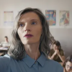 Nauczycielka w klasie, w tle widać innych ludzi, obsada filmu.