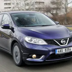 Fioletowy Nissan Pulsar w ruchu ulicznym. Wiele osób szuka nissan pulsar opinie przed zakupem.