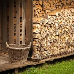 Ein Korb steht neben einem Holzstapel, bereit, das Holz im Ofen zu trocknen.