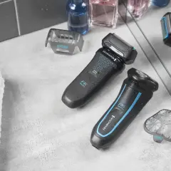 Dwie golarki elektryczne Remington R6 Wet/Dry, akcesoria i kosmetyki na szarym blacie.